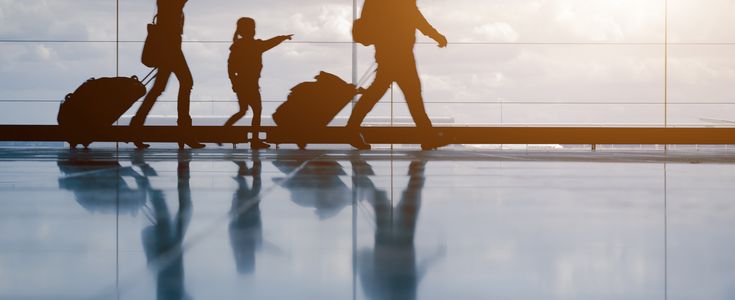 Silhouette of young family with luggage walking at airport