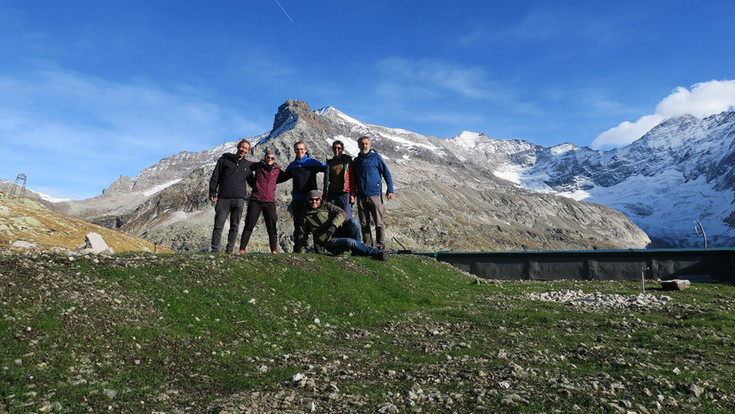 6 Personen auf einer Bergwise, dahinter ein hoher Berg.