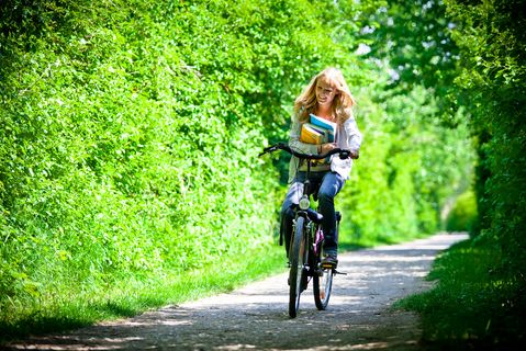 Frau balanciert mit Lehrbüchern auf einem Fahrrad