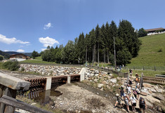 In the valley. The group arrives at a large mountain torrent featuring massive protective structures made of stone, concrete, and steel.