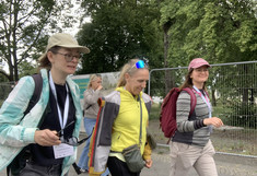 Three women walk past a park in good spirits