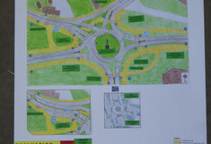 Entwurfsposter für die zweite Planungsvariante als Turbo-Kreisverkehr („Variant Turbo Roundabout“). Der farbig gestaltete Lageplan zeigt die optimierte Spurenführung und Querungshilfen. Das Poster listet die Vor- und Nachteile auf und bewertet die Variante grafisch in einer Vergleichstabelle.