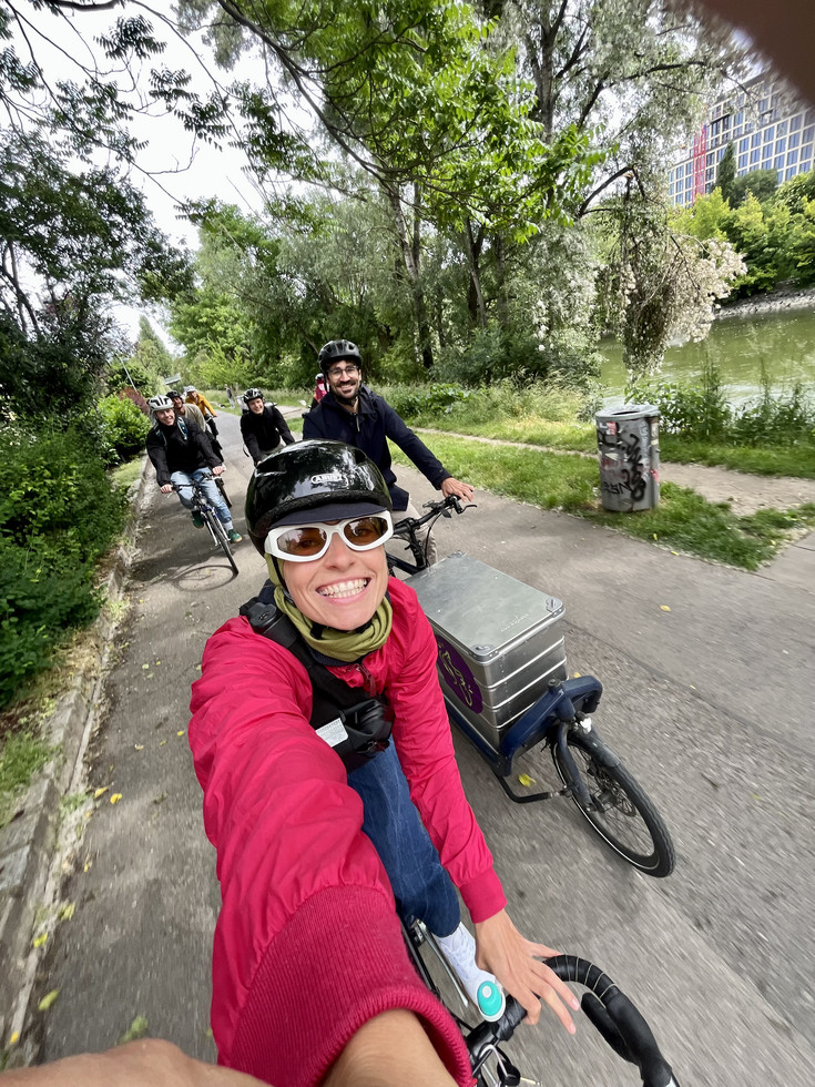 © BRIEFER, 2025 Selfie einer Radfahrerin in roter Jacke am Radweg, im Hintergrund 4 weitere RadfahrerInnen.