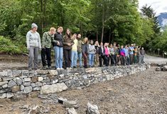 Studierende stehen auf der fertigen Trockensteinmauer