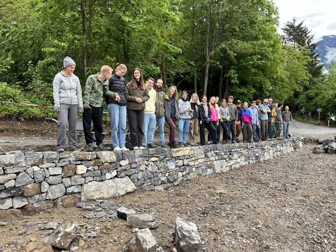 Studierende stehen auf der fertigen Trockensteinmauer