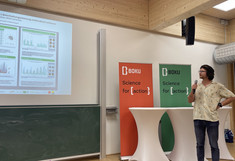 The presenter looks at his presentation slide on the large monitor and speaks into the microphone