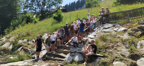 Im Tal. Die Gruppe kommt zu einem größeren Wildbach mit massiven Schutzbauwerken aus Stein und  Beton.