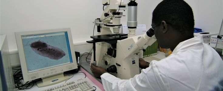 man in a lab coat working with a microscope