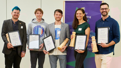 Gewinner*innen des BOKU Leading Lights Preis mit ihren Urkunden und Holzawards in Form eines Leuchtturms nach der offiziellen Verleihung