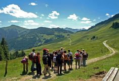 Berglandschaft im Sommer mit einer Gruppe von Studierenden in Wanderbekleidung im Vordergrund