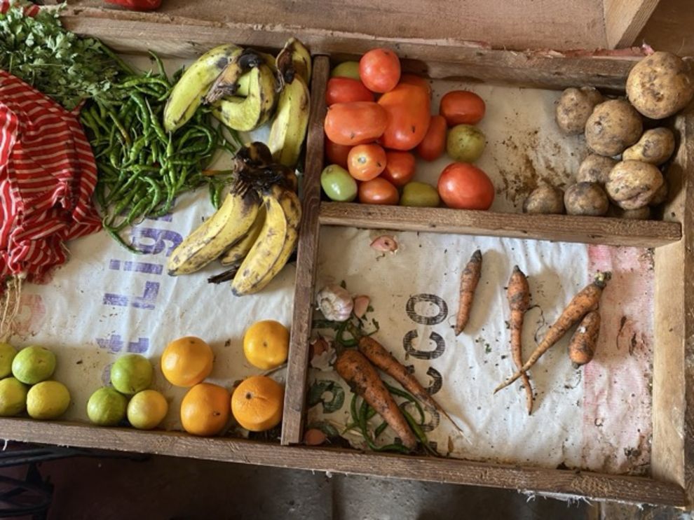 The image shows a nearly empty box with a few pieces of fruit and vegetables scattered inside. 