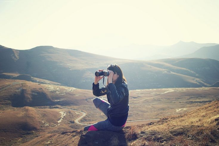 young woman with binoculars in landscape