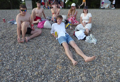 Eine Gruppe von sechs Teilnehmenden des Workshops nutzt die Freizeit, um gemeinsam an einem Kieselstrand an der Donau in Belgrad zu entspannen, sich zu unterhalten und bei kühlen Getränken das sonnige Wetter zu genießen.