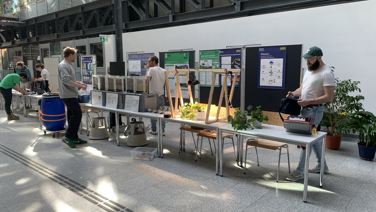 In der Aula werden die Stationen auf Tischen von mehreren Personen aufgebaut.