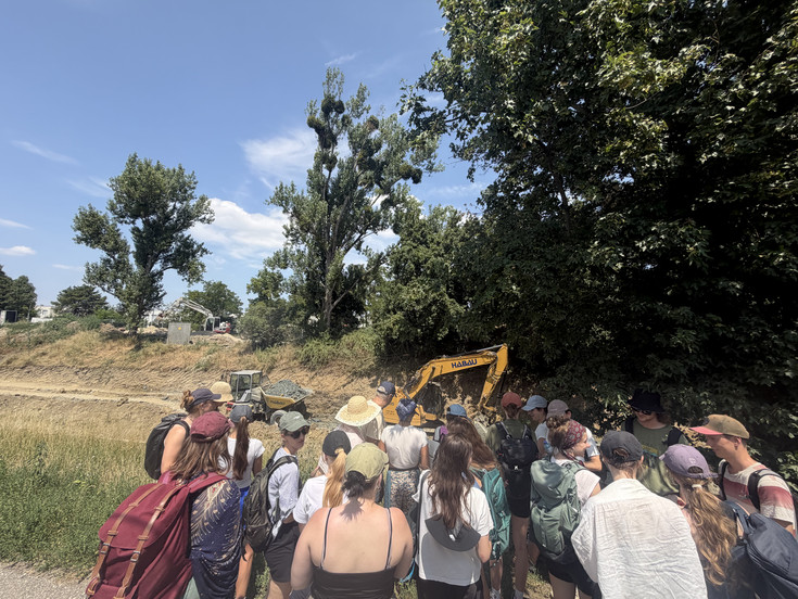 The excursion group at the Liesingbach stream, with excavation work in the background.