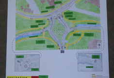 Entwurfsposter für die Umgestaltung des Knotenpunkts als T-Kreuzung („Variant T-Junction“). Neben einem kolorierten Lageplan mit neuen Fußgängerinseln und Radwegen enthält das Poster Vor- und Nachteile sowie eine tabellarische Bewertung (mittels Smileys), die die Variante mit dem Ist-Zustand vergleicht.