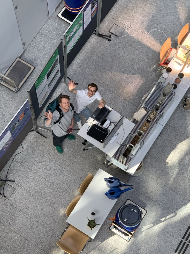 2 Mitarbeiter winken in die Kamera