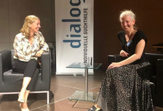 Nadja Springer und Lisa Wessely auf einer Bühne vor einem Banner des Vereins dialog sitzend.