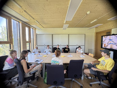 9 junge Leute sitzen bei einem Tisch