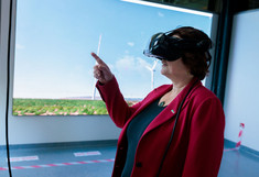 Eine Frau die eine VR Brille trägt, vor der LED Wall steht und mit einem erhobenen Finger.