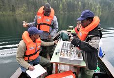 a group of three students from Africa on a boat taking samples from a European lake