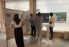 Four people are standing in front of the posters and discussing