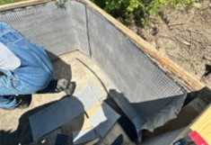 Arbeiter in Latzhose im inneren des Rahmens. Rahmen ca. 1 Meter mal 1,5  Meter und 0,7 Meter hoch.