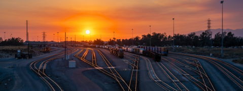 Foto: Bahnhof mit Locks und Waggons und im Vordergrund ein Schienennetz