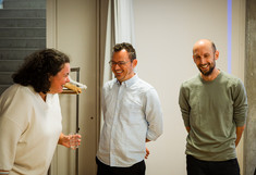 Drei Personen stehen nebeneinander und lachen