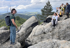 Some people stand or sit on boulders