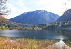 a calm autumn lake, behind it a large mountain (Austria)