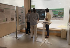 Three people are standing in front of a poster