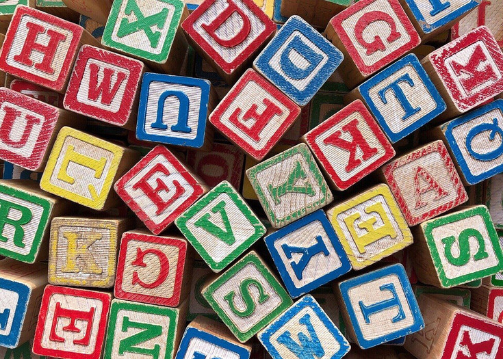 verschiedene bunte Holzwürfel mit Buchstaben drauf, durcheinander gemischt 