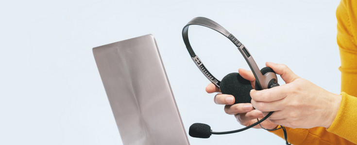 Laptop with headphones on wooden desk. Female hands