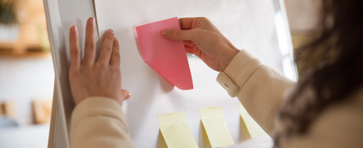 Female manager sticking blank paper notes on flipchart © teaser image: female manager sticking post its