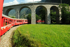 Swiss Red Train Bernina Express pass on Brusio Viaduct. It is a spectacular helicoidal stone bridge that fits the surrounding landscape and is located on the Bernina railway not far from Brusio railway station in Canton Grisons, Italy.